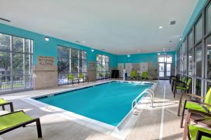 奥兰治堡SpringHill Suites by Marriott Orangeburg的一个带绿色椅子的酒店客房内的大型游泳池