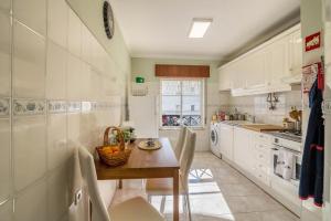 塔维拉Casa da Praia, Santa Luzia的厨房配有白色橱柜和木桌