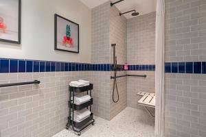 纽约Moxy NYC Lower East Side的浴室铺有白色和蓝色瓷砖,配有淋浴。