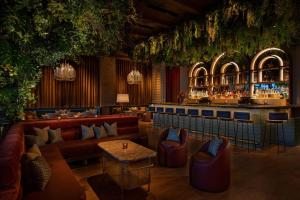 纽约Moxy NYC Lower East Side的一间配有沙发的餐厅和一间种植了植物的酒吧