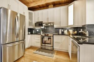 蒙特利尔STUNNING condos on ST Denis的厨房配有白色橱柜和不锈钢冰箱