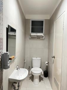 雅加达CASA CALMA HOTEL的一间带卫生间和水槽的浴室以及一台电视。