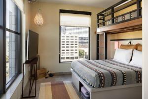 奥克兰Moxy Oakland Downtown的一间卧室设有一张床、一台电视和一个窗口。