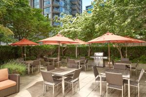 温哥华温哥华市中心万豪费尔菲尔德酒店的一个带桌椅和遮阳伞的庭院