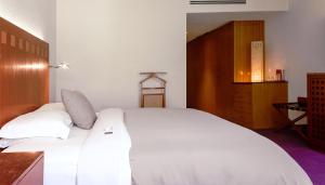 墨西哥城卡米奥真实酒店的卧室配有白色的床和木制橱柜。