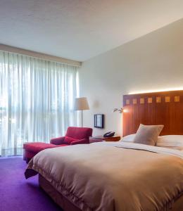 墨西哥城卡米奥真实酒店的一间卧室配有一张大床和一张红色椅子