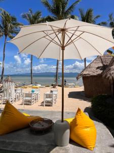 班泰Sea Love Beach Bar & Bungalows的沙滩上的白色遮阳伞和一些黄色物品