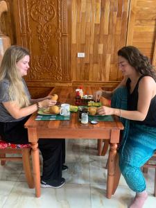 河江Sun Hà Giang Hotel的两个坐在餐桌上吃食物的女人