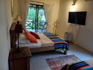 金巴亚Fincas Panaca Herreria 1 - San Judas的一间卧室配有一张床、一台电视和一个阳台