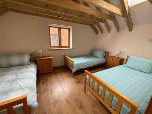诺里奇Charming Norfolk Barn Conversion in Barnham Broom的一间卧室设有两张床、一把椅子和一个窗户。