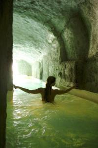 蓬扎圣多米蒂娜大酒店的站在洞穴的水中的女人