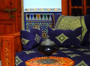 塞拉马尔科安达卢斯摩洛哥传统庭院住宅的一张带枕头的蓝色沙发以及一张桌子上的碗
