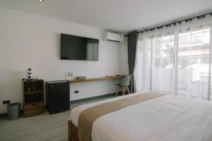 芭堤雅市中心ONE LODGE Pattaya的一间卧室设有一张床、一台电视和一个窗口。