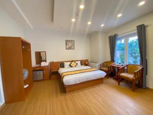 大叻Cherry Luxury Hotel的一间卧室配有一张床、一张书桌和一个窗户。