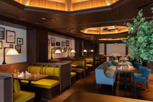 长崎长崎赛特雷格洛弗旅馆的餐厅设有桌子和黄色及蓝色的椅子
