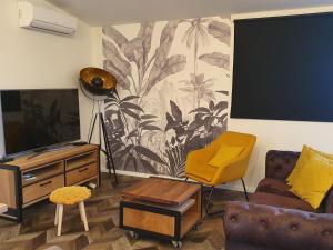 泰朗库尔Gite Le Gouttis的客厅配有电视和黄色椅子