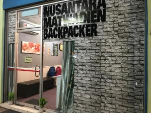 哥打京那巴鲁Nusantara Mattwaddien Hostel的砖墙边的标志