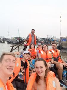 芹苴Enjoy Mekong Hostel的一群人穿着橙色救生衣,穿着船上的