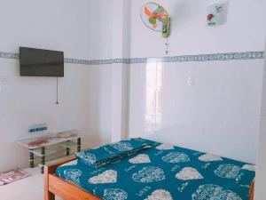 隆海Nhà nghỉ Thiên Thanh 1的一间卧室配有一张带蓝色床单的床和一台电视。