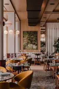 巴德加斯坦The Comodo Bad Gastein, a Member of Design Hotels的餐厅设有桌椅和大窗户。