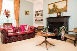 SetcheyThe Grange Manor House, Norfolk的客厅设有红色的沙发和壁炉