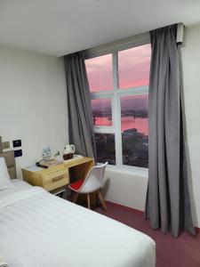 麦克坦Sempre Premier Inn - MACTAN AIRPORT HOTEL的客房设有床、书桌和窗户。