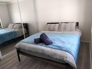 安娜湾Birubi Beach House的一间卧室配有一张带紫色枕头的床