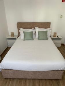 赞布热拉-杜马尔Alojamento Sudoeste的一张配有白色床单和绿色枕头的大床