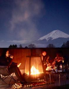 富士河口湖ヴィラ山間堂 Terrace Villa BBQ Bonfire Fuji view Annovillas的一群人坐在火堆旁,背景是山