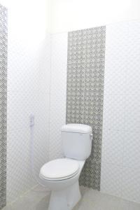 日惹The Cabin Hotel Ambasador的白色瓷砖墙内带卫生间的浴室