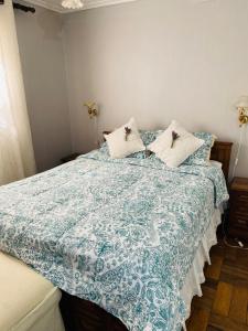 圣地亚哥Guest House GAAM Las Condes的一间卧室配有一张带蓝色和白色棉被的床