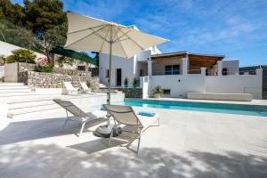 伊维萨镇Villa Casiopea的一个带两把椅子和一把遮阳伞的庭院,毗邻一个游泳池