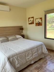 诺诺LA TOSCANA casas y suites的卧室设有一张白色大床和一扇窗户。