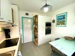 耶尔CAP SUD 83 APPART VUE MER 200m plages的厨房配有白色橱柜和桌子