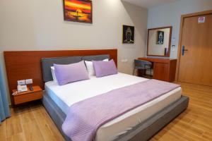 卡萨米尔6 Milje Hotel的一间卧室配有一张带紫色枕头的大床