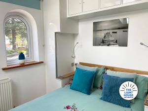 南安普敦Welcome to The Light House a tranquil city retreat.的一间卧室配有一张带蓝色枕头的床和一扇窗户。