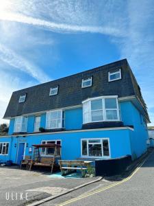 纽基Blue Room Hostel Newquay的前面有长凳的蓝色建筑