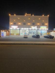 延布Etlalet Al-Sharm Apartments的夜间停在大楼前的三辆车