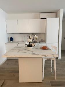 利尼亚诺萨比亚多罗BOUTIQUE HOME LIGNANO的厨房配有白色橱柜和鲜花桌