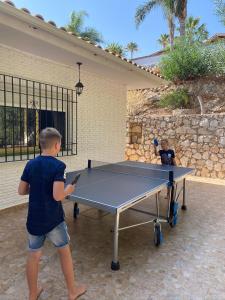 圣费德洛斯博利什Villa Mimosa sleeps 8 with Heated Pool的站在乒乓球桌旁的男孩