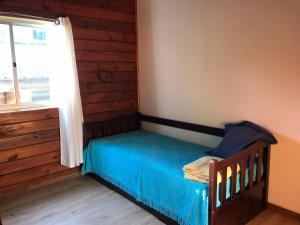 拉帕洛马Cabaña del Mar en La Paloma的一间卧室配有一张带蓝色毯子的床和窗户。