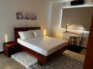 卢萨卡Smart Stay Eco Friendly AirBnB的一间卧室配有一张床和一张桌子及凳子