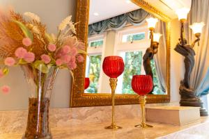 格拉玛多Le Boutique Hotel Gramado - Exclusivo para Casais的两瓶带红蜡烛的花瓶,放在镜子前的桌子上