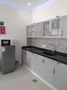 阿哈达منتجع الجزيرة الخضراء的厨房配有白色橱柜、水槽和冰箱。