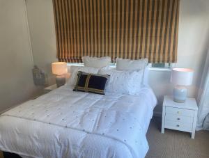 汉密尔顿CBD Apartment, River View的卧室配有白色床、两盏灯和一扇窗户。