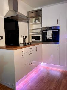 曼彻斯特Salford Quays Apartment, Manchester的厨房配有白色橱柜和LED照明