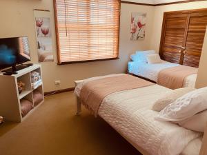 LindenParadise Lodge - Blue Mountains Wonderland的一间卧室配有两张床和一台平面电视