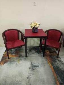 巴佐Homestay CikguRose UMK的两张椅子和一张红色桌子,上面有鲜花