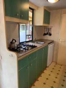维亚雷焦Comfortabele familie chalets met veranda incl airco dichtbij zee!的厨房配有绿色橱柜和炉灶。 顶部烤箱