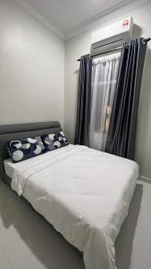 Guar ChempedakEl Manzil Homestay with Pool的一张带枕头的床和一个窗户